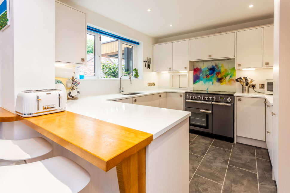 Open plan white kitchen diner. Round white dining table with blue chairs