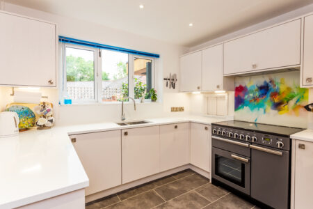 Open plan white kitchen diner. Round white dining table with blue chairs