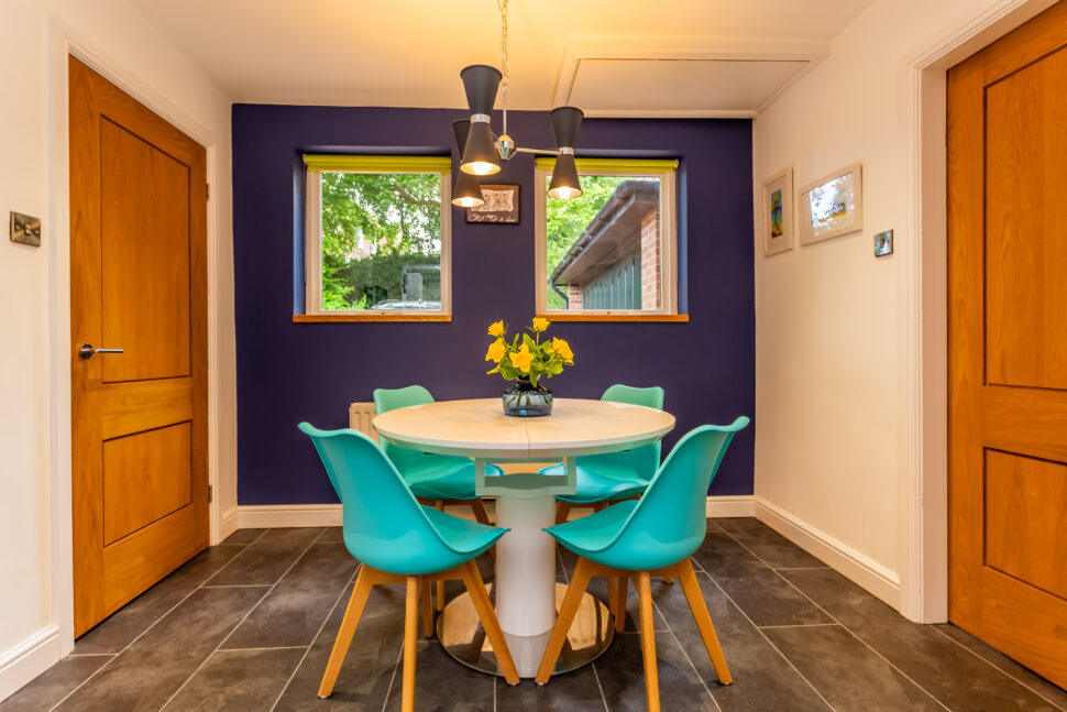 Open plan white kitchen diner. Round white dining table with blue chairs