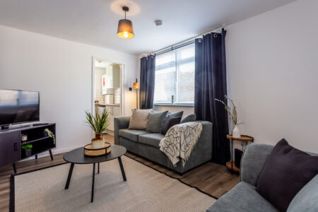 Off white living room with grey feature wall. Black coffee table. Grey curtains