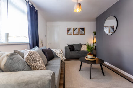 Off white living room with grey feature wall. Black coffee table. Grey curtains