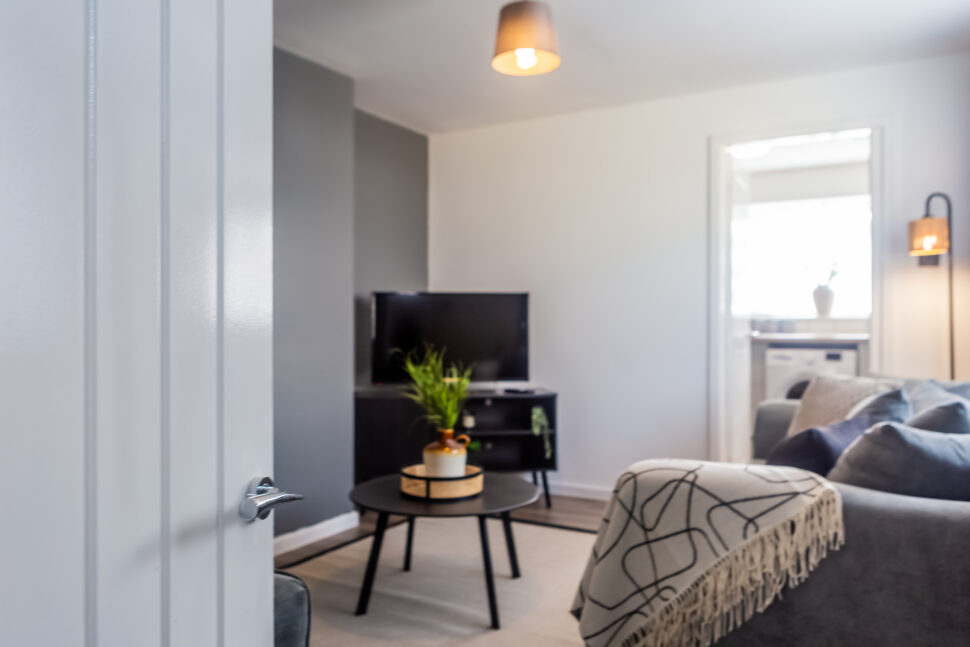 Off white living room with grey feature wall. Black coffee table. Grey curtains