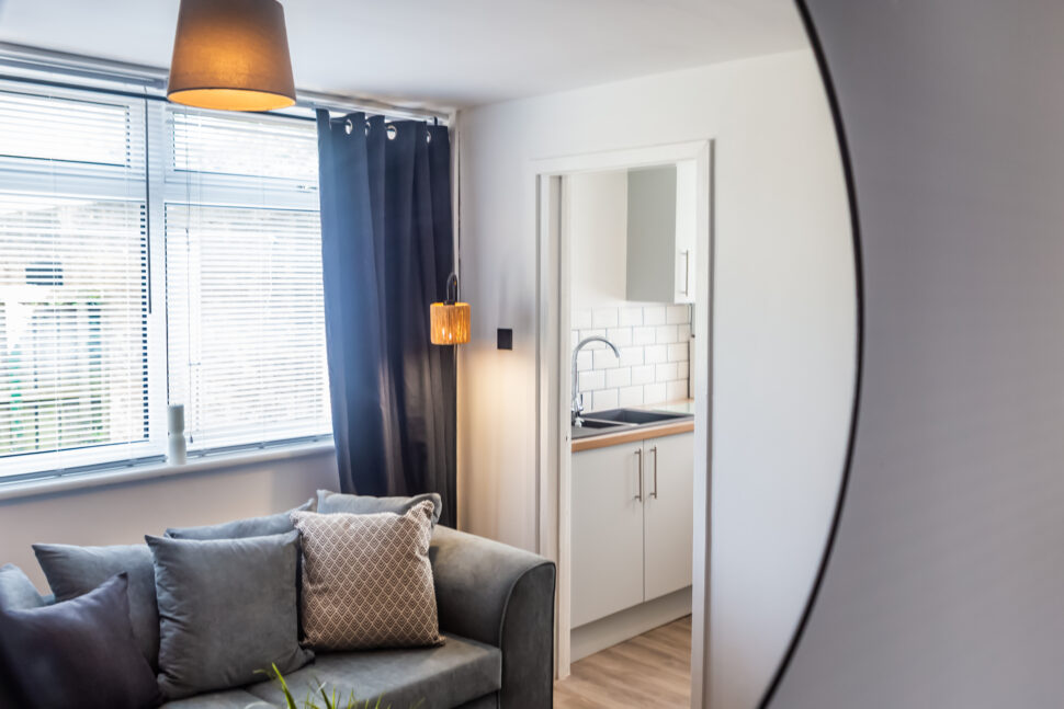 Off white living room with grey feature wall. Black coffee table. Grey curtains