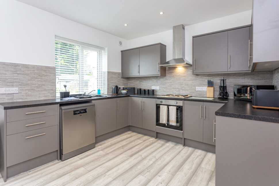 Grey u shaped kitchen with black worktops