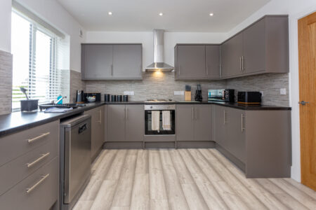 Grey u shaped kitchen with black worktops