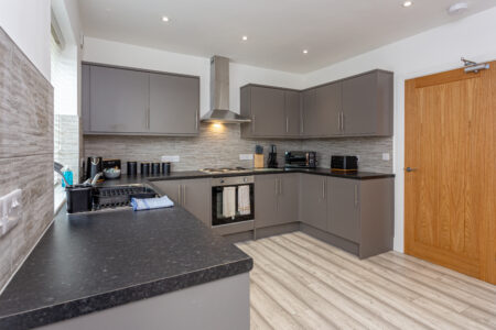 Grey u shaped kitchen with black worktops