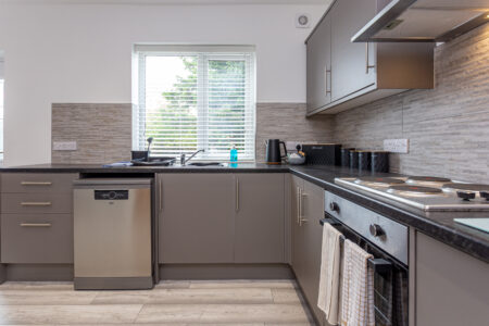 Grey u shaped kitchen with black worktops