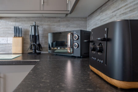 Grey u shaped kitchen with black worktops