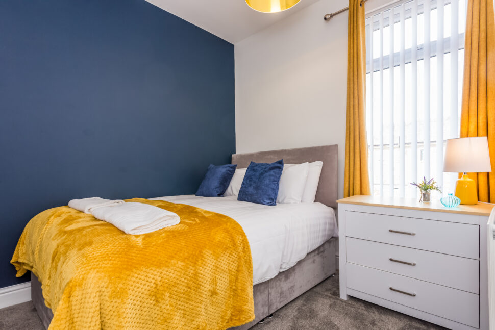 Navy double bedroom with yellow accessories