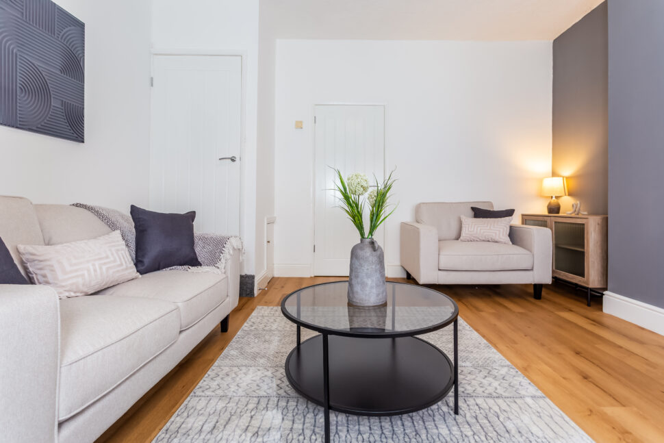 Off white living room. Beige Sofas. Black circular coffee table. Large rug