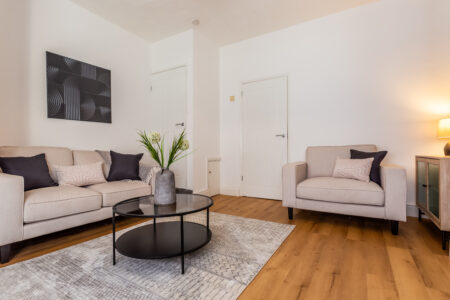 Off white living room. Beige Sofas. Black circular coffee table. Large rug