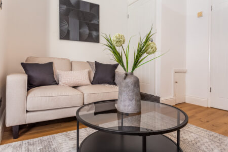 Off white living room. Beige Sofas. Black circular coffee table