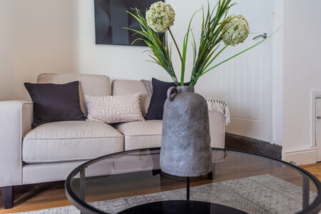 Off white living room. Beige Sofas. Black circular coffee table