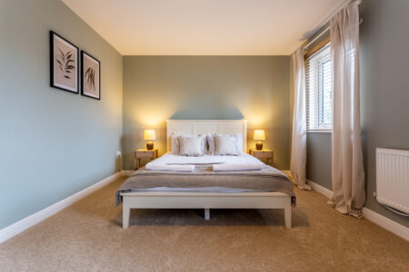 Light blue bedroom. Off-white king bed. Oak bedside tables