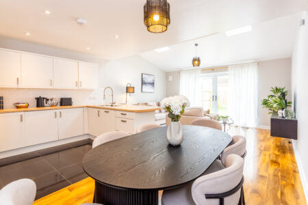 White kitchen with peninsular island with oak worktops. Black dining table