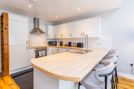 White kitchen with peninsular island with oak worktops