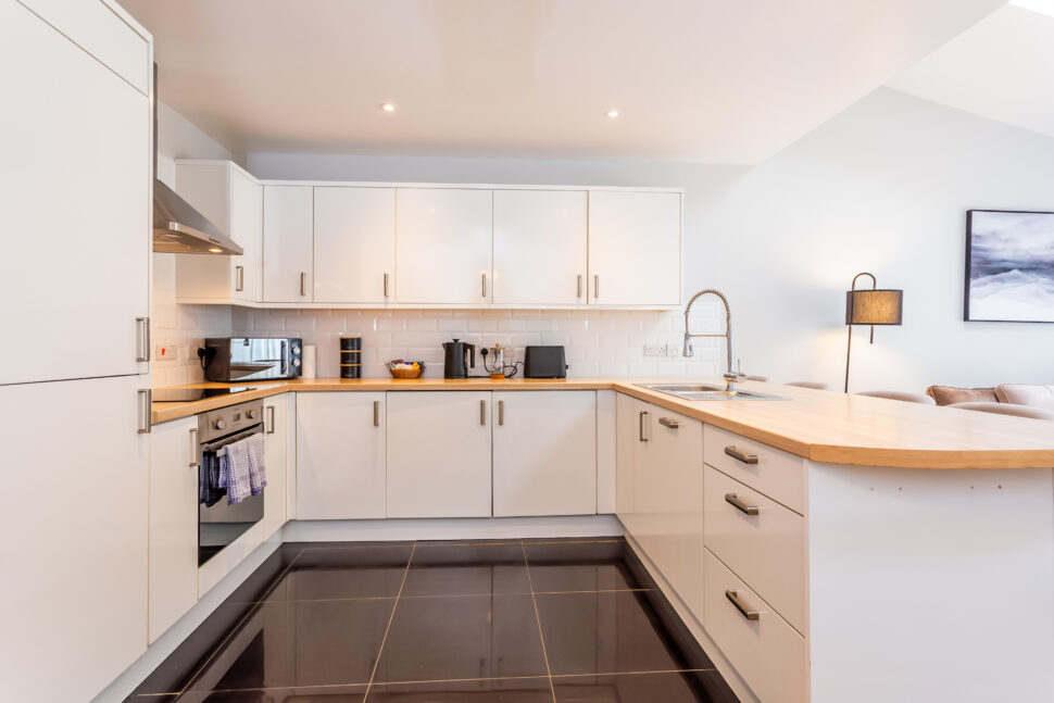 White kitchen with peninsular island with oak worktops