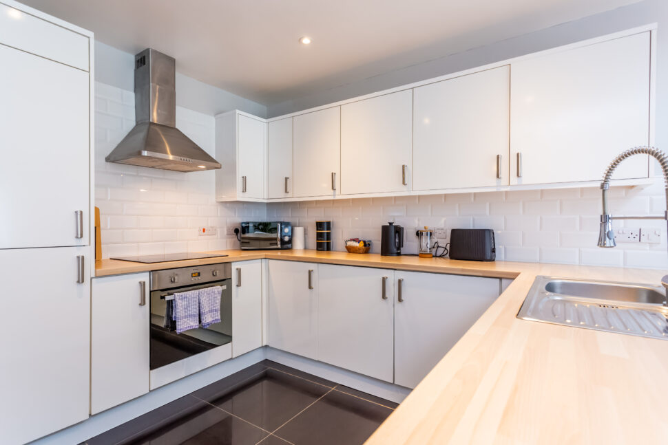 White kitchen with peninsular island with oak worktops