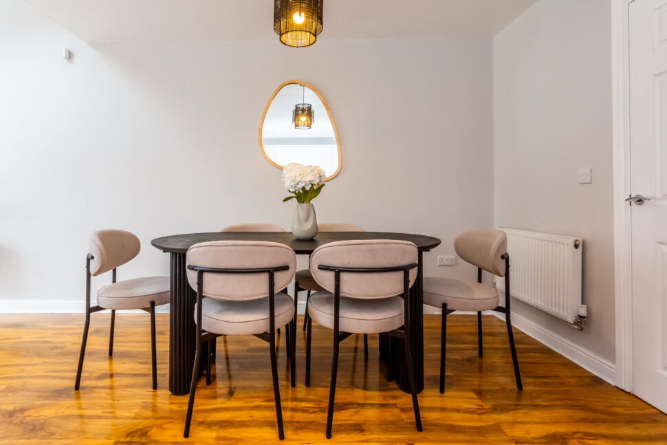 Black dining table beige chairs. Pebble mirror