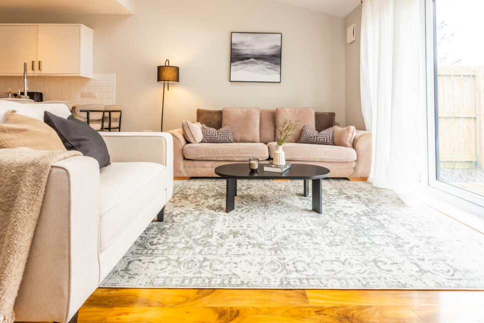 Beige living room with ammonite walls. Black coffee table. Large rug