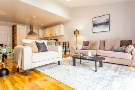 Beige living room with ammonite walls. Black coffee table. Large rug