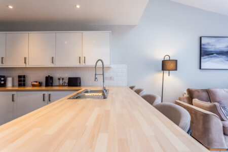 White kitchen with peninsular island with oak worktops