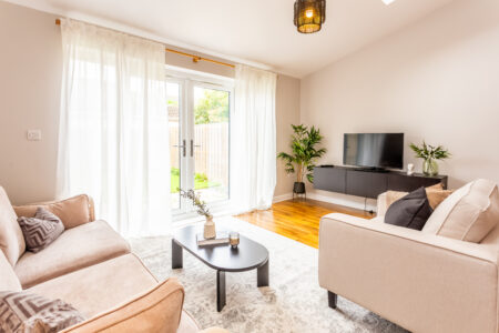 Beige living room with ammonite walls. Black coffee table. Black media unit