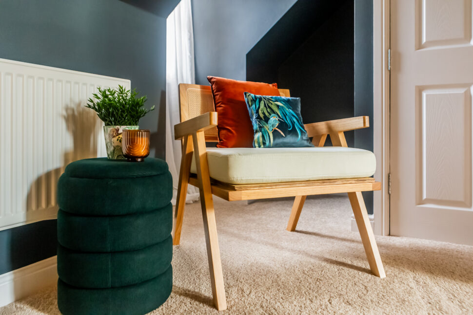 Studio green bedroom. Oak rattan and cream accent chair. Green ottoman