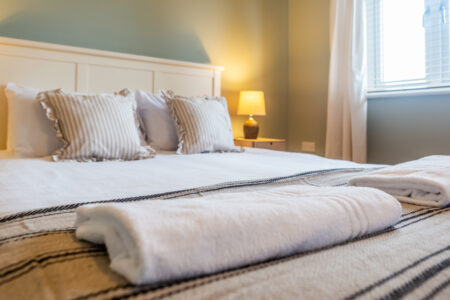 Light blue bedroom. Off-white king bed. Oak bedside tables