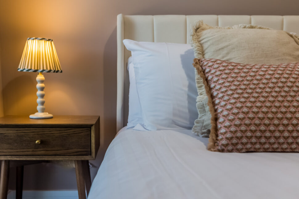 Toast Stays, second bedroom, showing close up shot of one side of the bed with scatter cushions, bedside cabinet and ambient lighting
