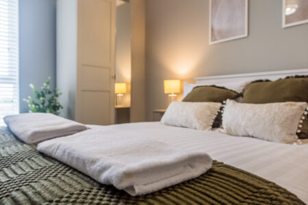 Toast Stays, close up shot looking over the bed showcasing the throw, guest towels and ambient lighting