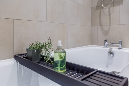 Toast Stays, bathtub with bath shelf holding a rosemary plant and body wash